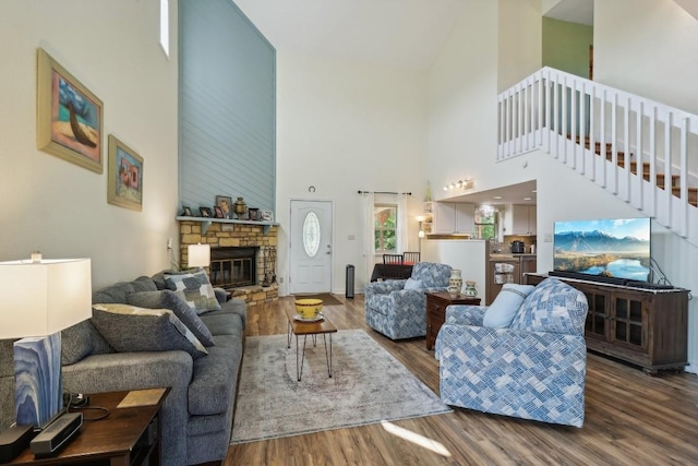 living area featuring a fireplace, stairs, and wood finished floors