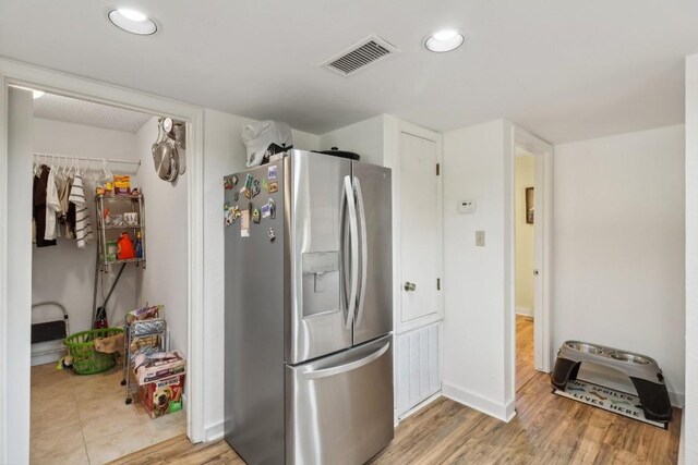 kitchen with visible vents, stainless steel fridge, light wood-style flooring, and baseboards