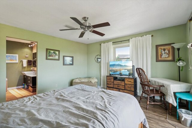 bedroom featuring ensuite bath, wood finished floors, visible vents, and ceiling fan