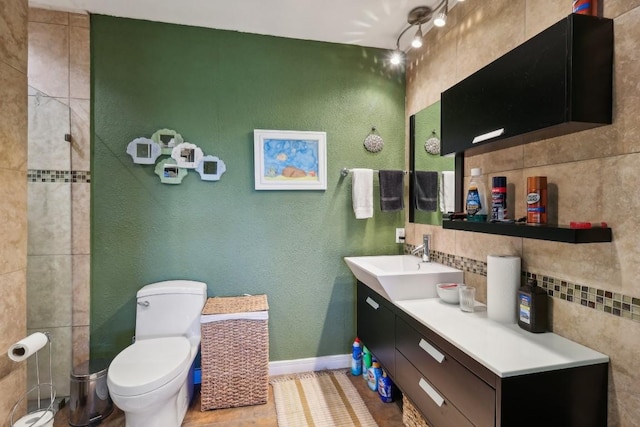 full bathroom featuring toilet, backsplash, baseboards, vanity, and a textured wall