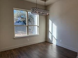 unfurnished dining area with plenty of natural light, dark wood-type flooring, and a notable chandelier