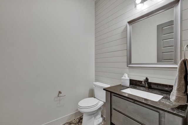 bathroom with vanity, wood walls, and toilet