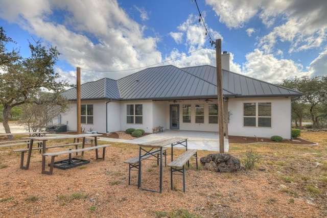 rear view of property with ceiling fan and a patio