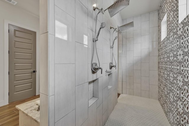 bathroom with a tile shower and hardwood / wood-style floors