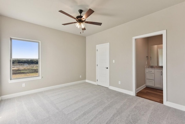 unfurnished bedroom with ensuite bathroom, ceiling fan, and light colored carpet