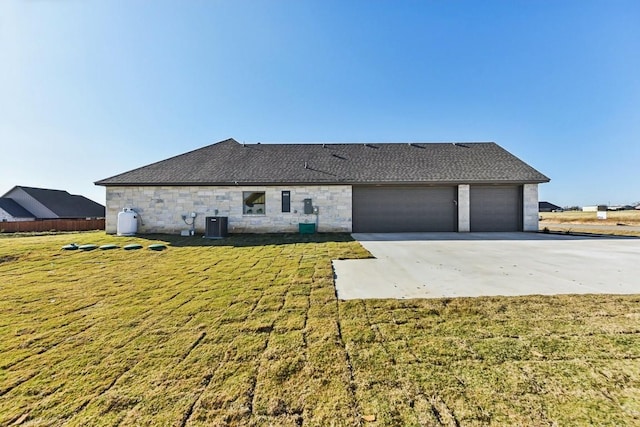 rear view of property with central air condition unit, a yard, and a garage