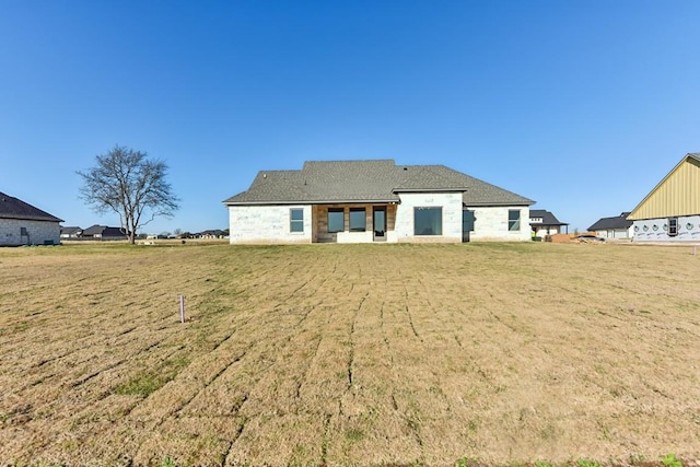 rear view of property featuring a lawn