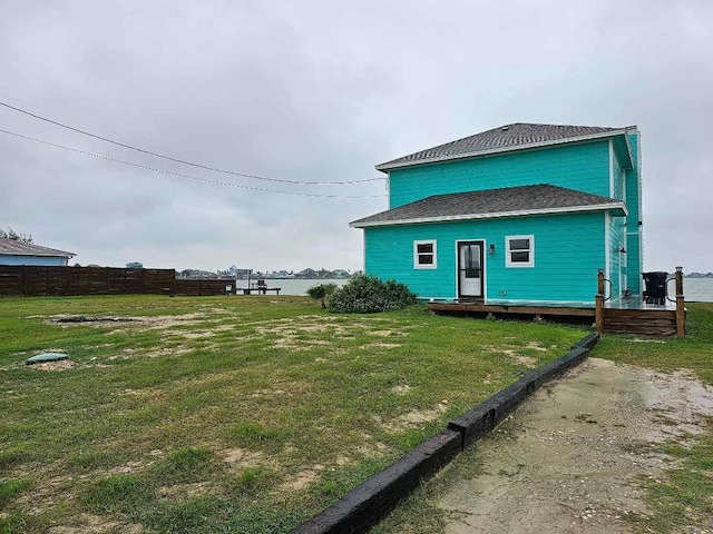 rear view of house featuring a water view and a yard