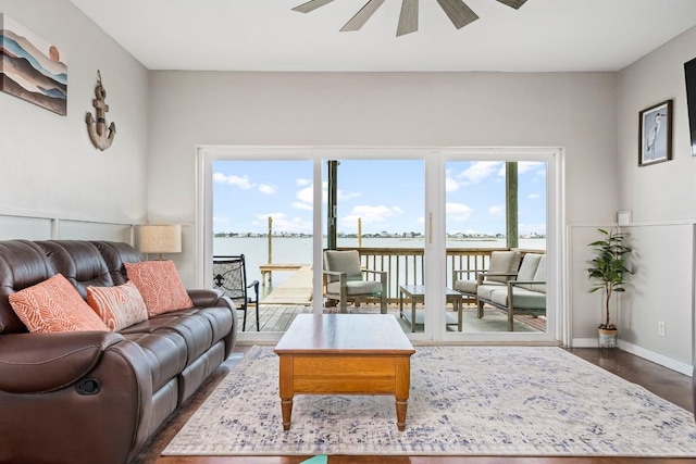 living room featuring ceiling fan, dark hardwood / wood-style flooring, and a water view