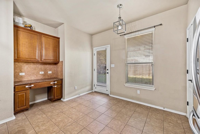 interior space with stainless steel refrigerator, light tile patterned flooring, and hanging light fixtures