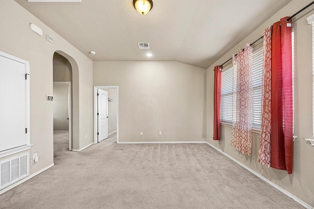 carpeted empty room with vaulted ceiling