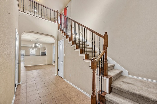 staircase with tile patterned flooring and a towering ceiling