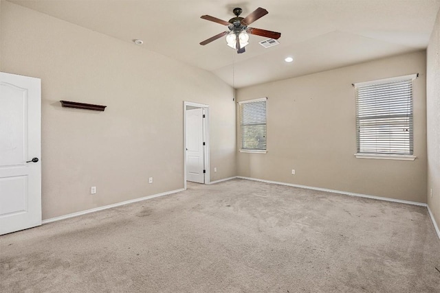 spare room with light colored carpet, vaulted ceiling, and ceiling fan