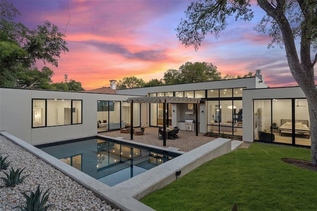 back house at dusk featuring a yard and a patio