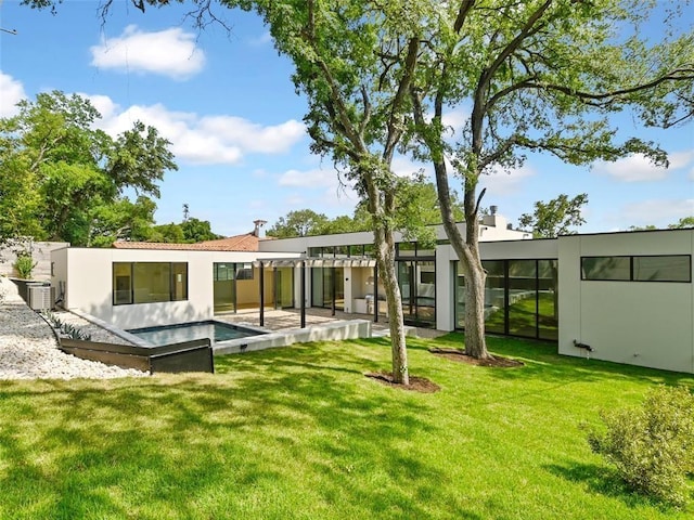 rear view of property featuring a lawn, a patio area, and central AC unit