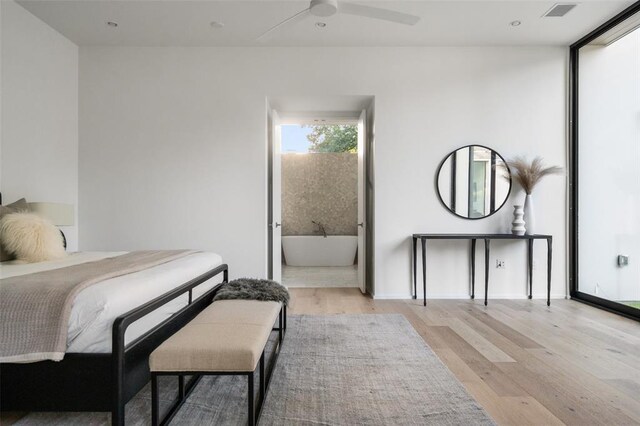 bedroom featuring ceiling fan, light wood-type flooring, and ensuite bath