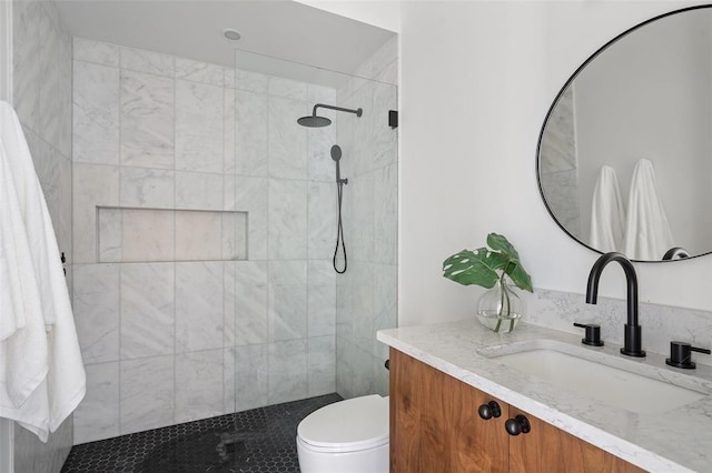 bathroom featuring a tile shower, vanity, and toilet