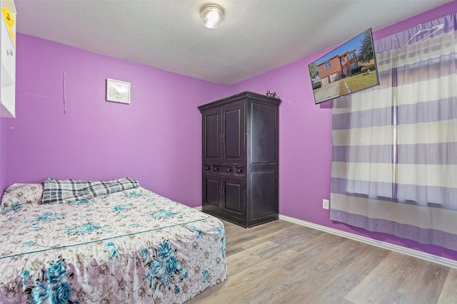 bedroom with a textured ceiling and light hardwood / wood-style flooring