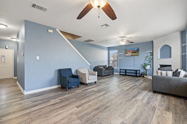 living room featuring hardwood / wood-style flooring, ceiling fan, and a fireplace