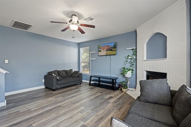 living room featuring hardwood / wood-style flooring, a brick fireplace, and ceiling fan