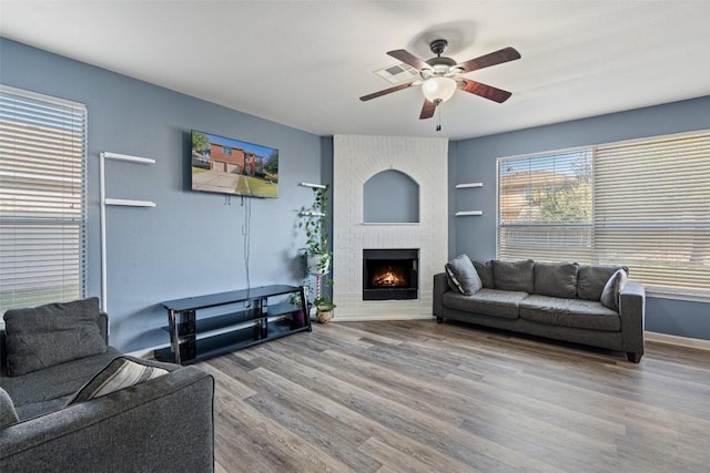 living room featuring ceiling fan, light hardwood / wood-style floors, and a brick fireplace