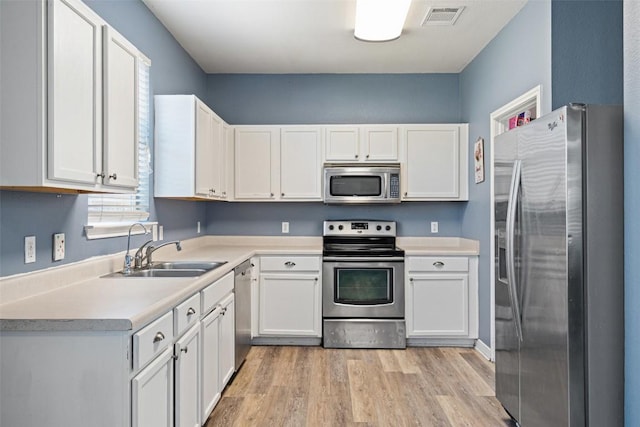 kitchen with appliances with stainless steel finishes, white cabinetry, plenty of natural light, and sink