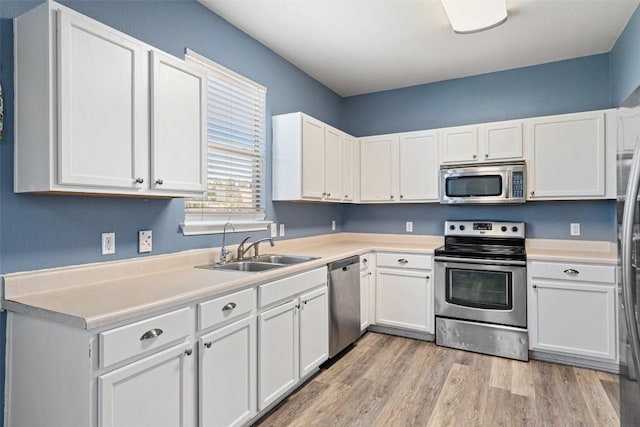 kitchen with white cabinets, light wood-type flooring, sink, and appliances with stainless steel finishes