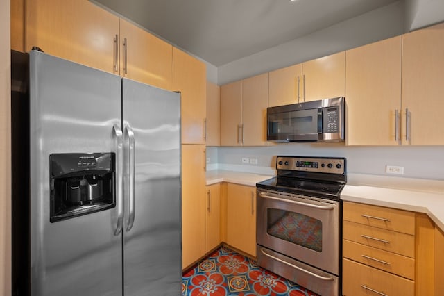 kitchen featuring dark tile patterned floors, stainless steel appliances, and light brown cabinetry