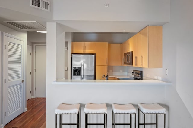 kitchen featuring kitchen peninsula, appliances with stainless steel finishes, a kitchen breakfast bar, sink, and light brown cabinets