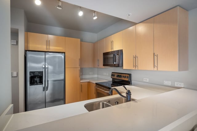 kitchen with kitchen peninsula, appliances with stainless steel finishes, light brown cabinetry, and sink