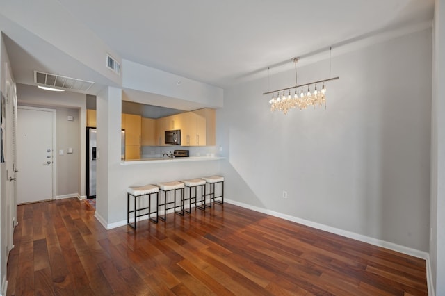 kitchen featuring dark hardwood / wood-style flooring, light brown cabinets, a breakfast bar, and appliances with stainless steel finishes