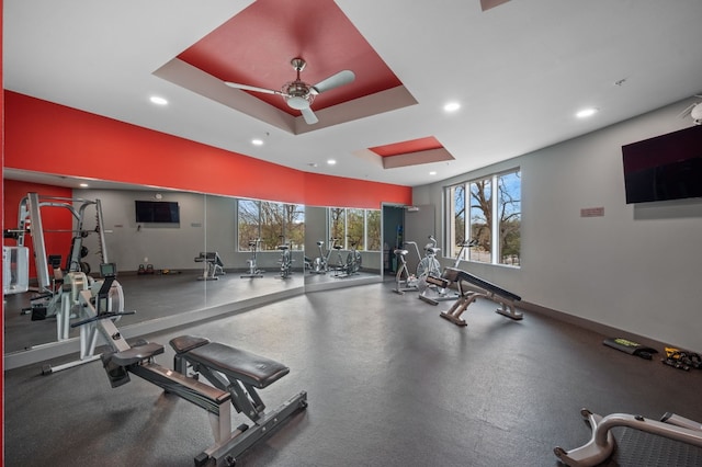 exercise room with a tray ceiling and ceiling fan