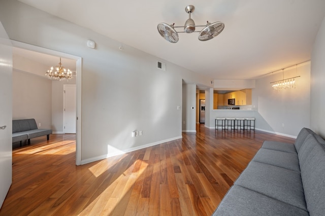 living room with wood-type flooring and ceiling fan with notable chandelier