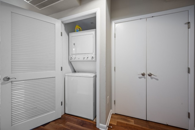 laundry room with stacked washing maching and dryer and dark hardwood / wood-style floors