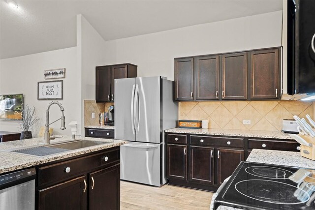 kitchen with appliances with stainless steel finishes, sink, decorative backsplash, dark brown cabinets, and light wood-type flooring