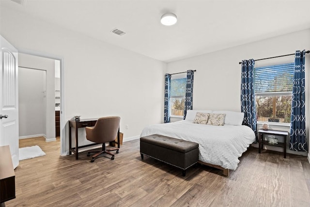 bedroom with multiple windows, wood finished floors, and baseboards