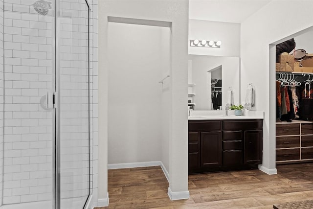 bathroom with a shower stall, wood finished floors, vanity, and a spacious closet