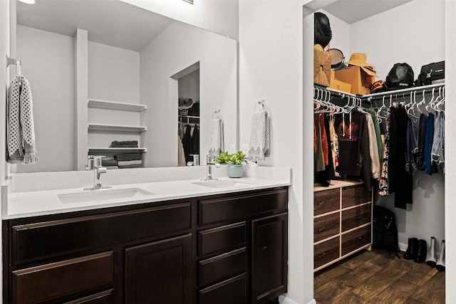 bathroom featuring wood finished floors, double vanity, and a walk in closet