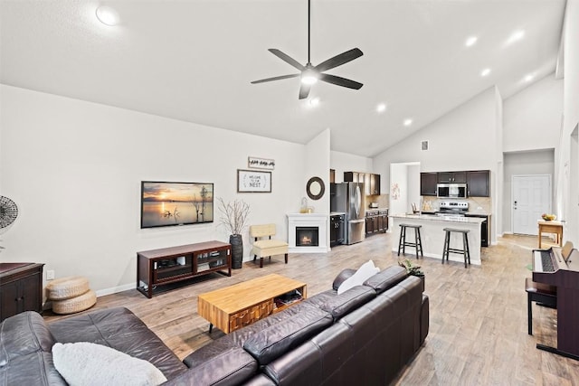 living room with ceiling fan, sink, high vaulted ceiling, and light hardwood / wood-style floors