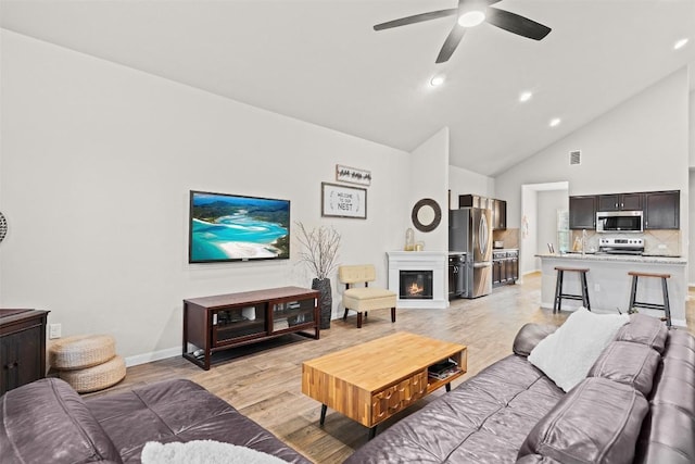 living room featuring ceiling fan, high vaulted ceiling, and light hardwood / wood-style flooring