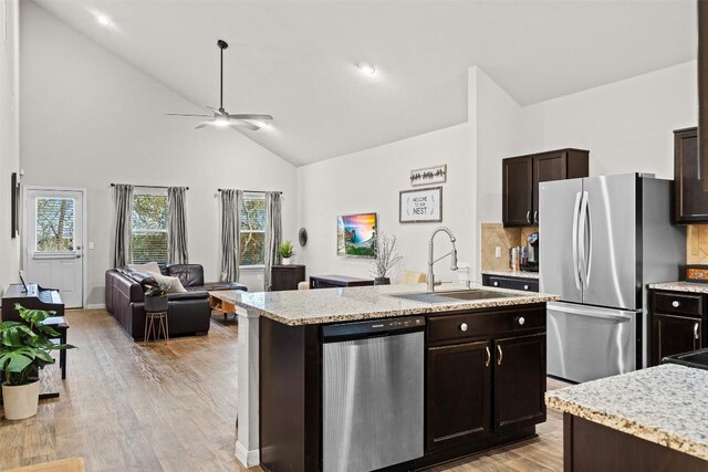 kitchen with sink, appliances with stainless steel finishes, a kitchen island with sink, backsplash, and dark brown cabinets