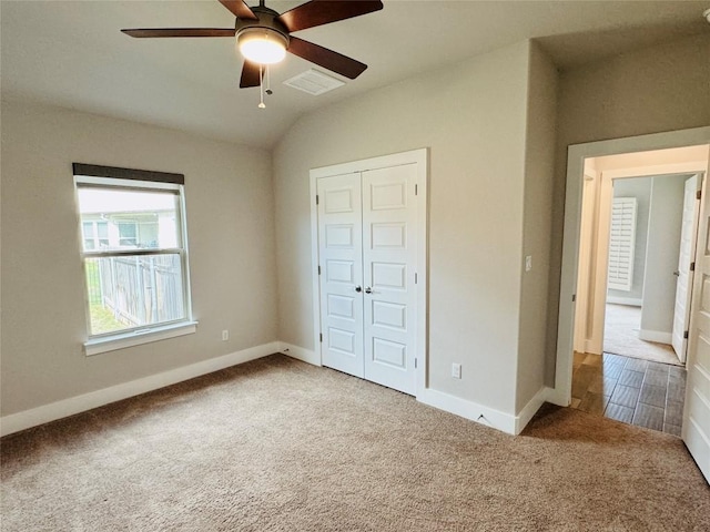 unfurnished bedroom with ceiling fan, a closet, carpet floors, and vaulted ceiling