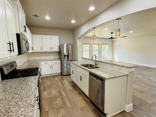125 Millsaps Ct, Bastrop, TX 78602 - kitchen with stainless steel appliances, light wood-type flooring, a sink, an island with sink, and arched walkways