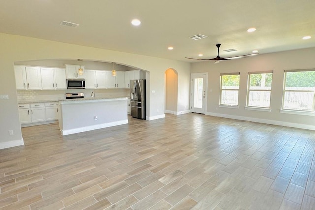 125 Millsaps Ct, Bastrop, TX 78602 - unfurnished living room with ceiling fan, arched walkways, recessed lighting, baseboards, and light wood-style flooring