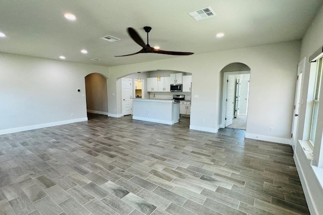 125 Millsaps Ct, Bastrop, TX 78602 - unfurnished living room with a ceiling fan, arched walkways, recessed lighting, baseboards, and light wood-style flooring
