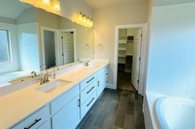 125 Millsaps Ct, Bastrop, TX 78602 - bathroom featuring double vanity, a garden tub, a spacious closet, and wood finish floors