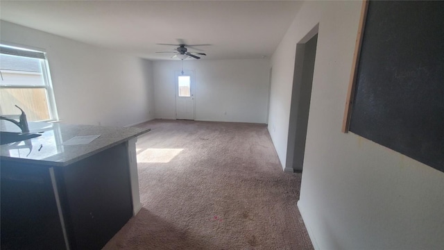 unfurnished living room featuring light carpet and ceiling fan