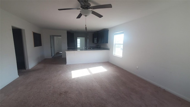 unfurnished living room featuring dark carpet and ceiling fan