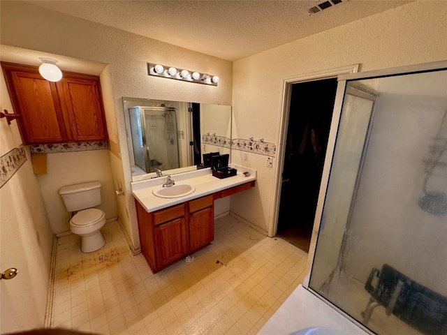 bathroom featuring a shower with door, vanity, a textured ceiling, and toilet