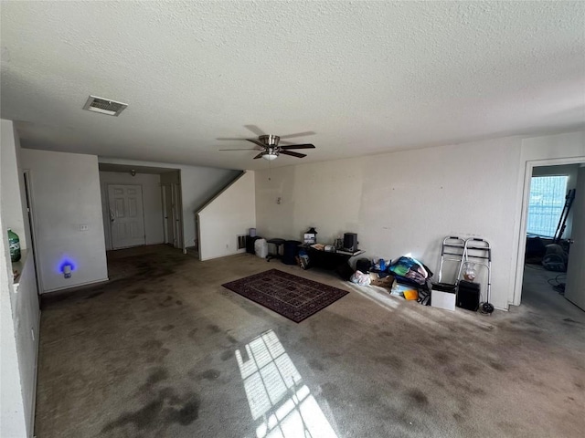 unfurnished living room featuring a textured ceiling, carpet floors, and ceiling fan